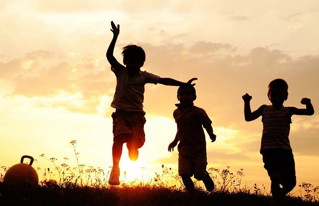 80 Summer Quotes for Kids to Make It a Fun and Happy Season Happy kids running in the grass at sunset.